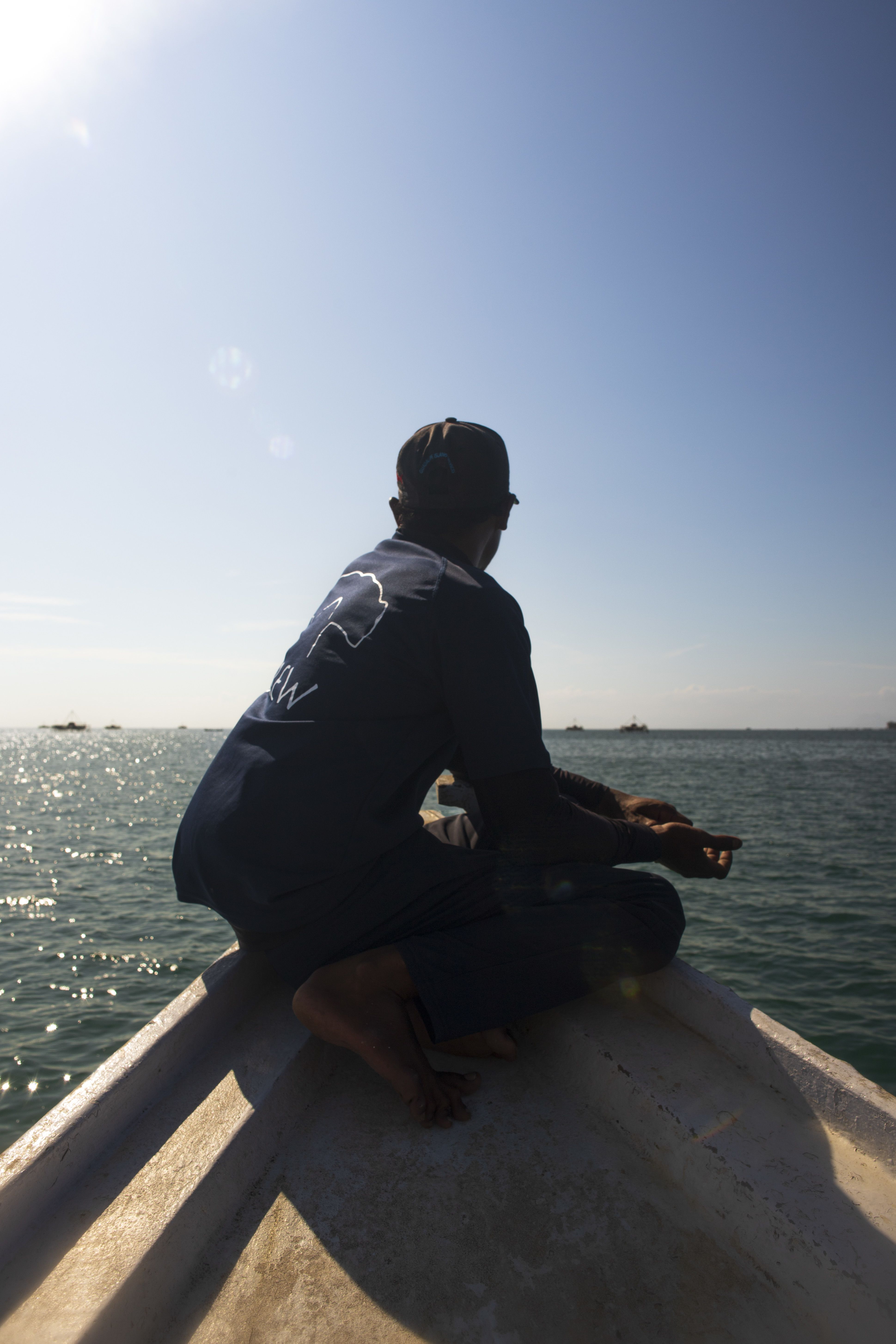 A man sits on the bow of Project Hiu's ship